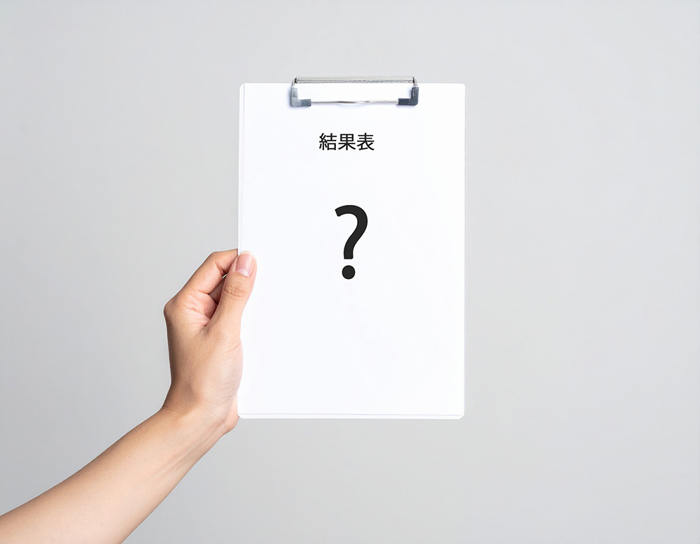？マークが書かれた結果表を左手で持っている